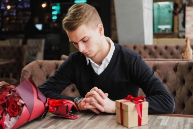 Genç bir adam bir restoranda oturur ve bir kız arkadaş, kız arkadaşı veya karısı ile bir toplantı için bekliyor. Çiçek ve hediye yakınındaki, saat bakarak vardır.