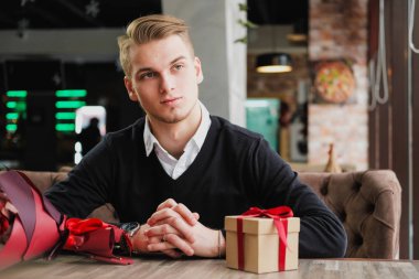 Genç bir adam bir restoranda oturur ve bir kız arkadaş, kız arkadaşı veya karısı ile bir toplantı için bekliyor. Çiçek ve hediye yakınındaki, saat bakarak vardır.