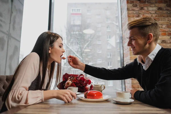 Aşık, bir erkek ve bir kadın, bir çift yemek kaşık ile bir kırmızı kalp şeklinde tatlı bir kafede. — Stok fotoğraf