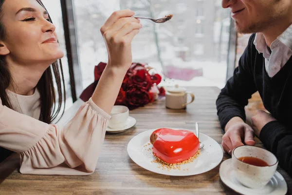 Aşık, bir erkek ve bir kadın, bir çift yemek kaşık ile bir kırmızı kalp şeklinde tatlı bir kafede.