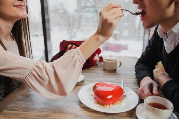 Aşık, bir erkek ve bir kadın, bir çift yemek kaşık ile bir kırmızı kalp şeklinde tatlı bir kafede.