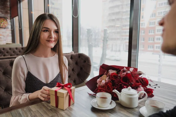 Genç bir adam bir kıza, eşi, pencere kenarındaki bir kafede bir hediye bir kırmızı kurdele ile verir.