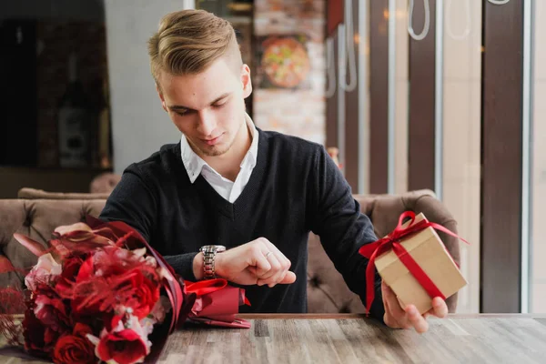 Genç bir adam bir restoranda oturur ve bir kız arkadaş, kız arkadaşı veya karısı ile bir toplantı için bekliyor. Çiçek ve hediye yakınındaki, saat bakarak vardır.