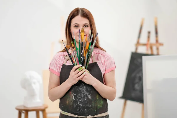 Молодая художница с кисточками и красками в белой студии . — стоковое фото