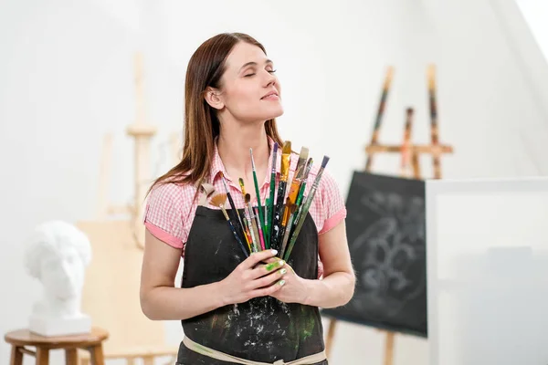 Fırçalar ve boya beyaz Studio ile genç bir kadın sanatçı. — Stok fotoğraf