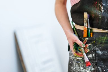 Kadın Sanatçılar bir fırça ve kırmızı boya ile ver. Siyah önlük, beyaz arka plan.