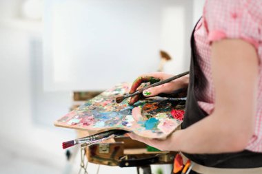 Sanatçılar araçları şövale üzerinde. Fırçalar, boyalar ve tuval.