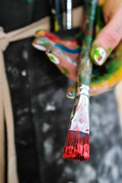 Mujeres artistas mano con un pincel y pintura roja. Delantal negro, fondo blanco . —  Fotos de Stock