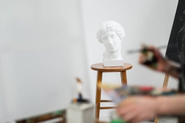Genç güzel kız ressam beyaz bir stüdyoda bir şövale üzerinde tuval üzerinde çizer.