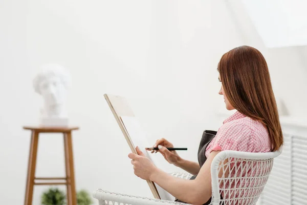 Ung kvinna konstnären drar en penna på duk. — Stockfoto