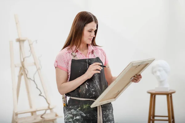 Ung kvinna konstnären drar en penna på duk. — Stockfoto