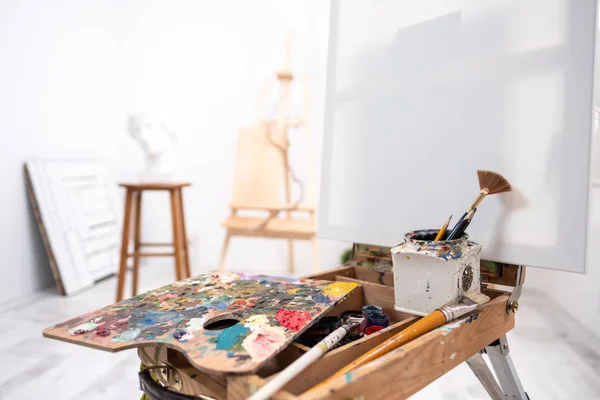 Interior del estudio blanco del artista, persona creativa. caballete, cepillos, cabeza de yeso y figuras. Ático, techos altos . — Foto de Stock