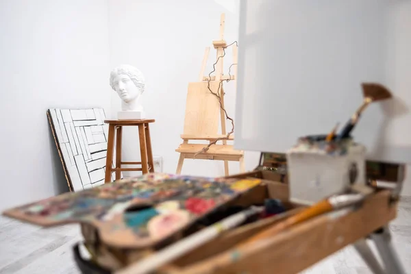 Interior do estúdio branco do artista, pessoa criativa. Easel, escovas, cabeça de gesso e figuras. Sótão, tectos altos . — Fotografia de Stock
