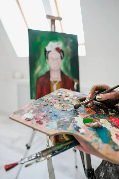 Молодая красивая девушка-художник в белой студии рисует на мольберте на холсте . — стоковое фото