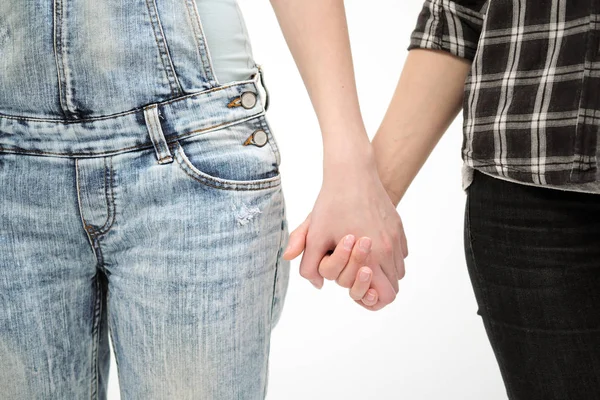 Dos chicas en jeans se toman de las manos de cerca. Fondo blanco. Homosexual lesbiana pareja . — Foto de Stock