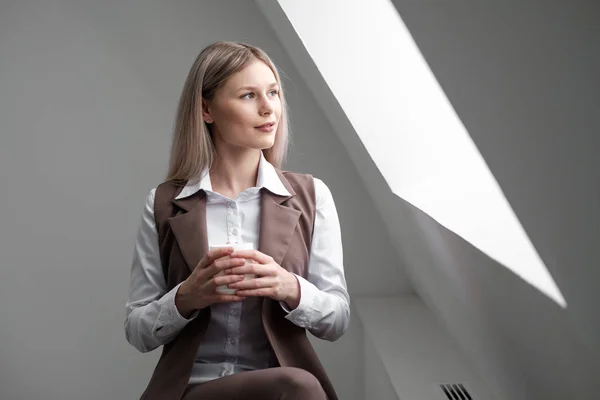 Blond meisje in een pak werkt op een computer in een witte lichte kantoor. — Stockfoto