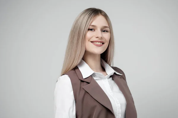Porträtt av en ung vacker blond kvinna på en grå bakgrund i brun kostym. — Stockfoto