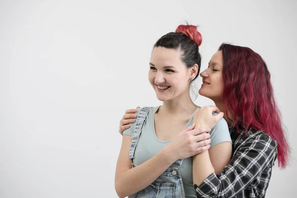 Two girls hug on a white background. Homosexual lesbian couple. Casual clothes. — Stock Photo, Image