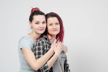 İki kız beyaz bir arka plan üzerinde sarıl. Homoseksüel lezbiyen çift. Rahat kıyafetler.