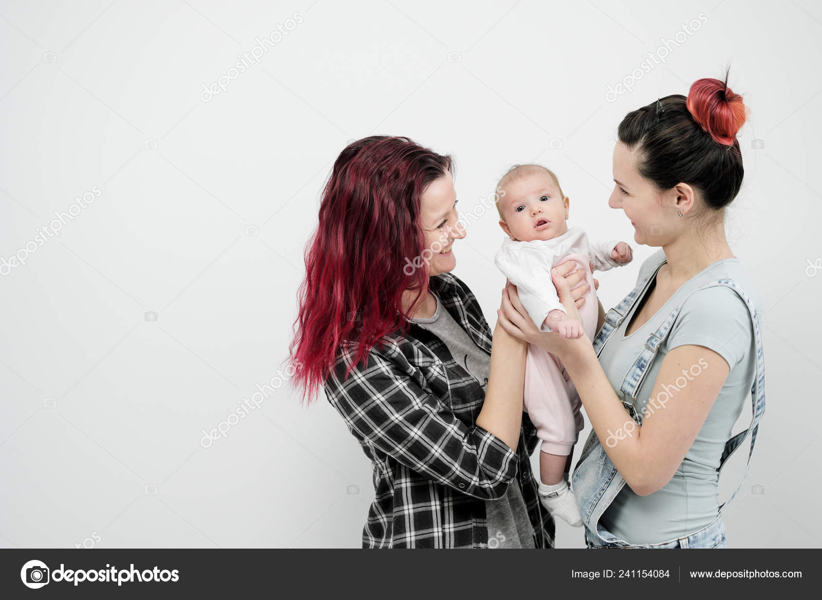 Two young women with a baby on a white background