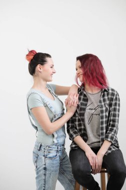 İki kız beyaz bir arka plan üzerinde sarıl. Homoseksüel lezbiyen çift. Rahat kıyafetler.