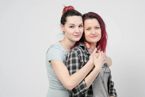 Two girls hug on a white background. Homosexual lesbian couple. Casual clothes. — Stock Photo, Image