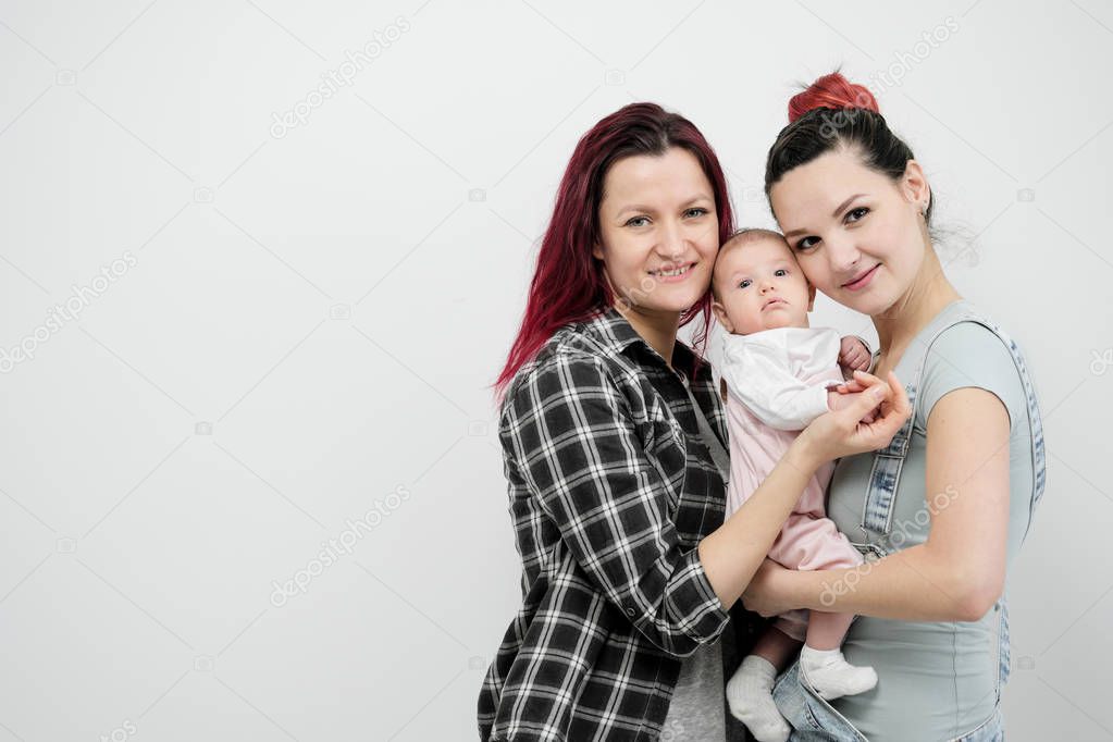 Two young women with a baby on a white background. Same-sex marriage and adoption, homosexual lesbian couple.