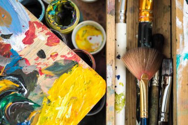 Boyalar farklı renkler ve sanatçı yakın çekim şövale üzerinde kirli fırçalar.