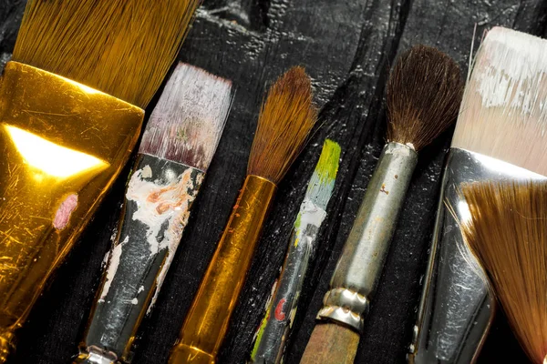 Sanatçılar, Boya fırçaları üst üste siyah ahşap zemin araçlardır. — Stok fotoğraf