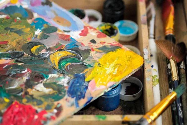 A különböző színek és a szennyezett kefék a festőállvány a művész közelről festékek. — Stock Fotó