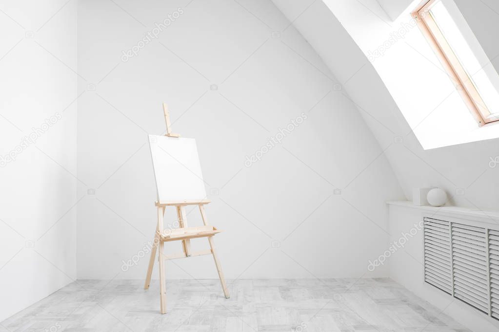 White and bright studio with a window. Workspace of the artist. Easel, canvases and plaster figures for learning to draw.