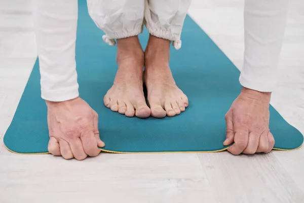 Um professor e treinador do sexo masculino em roupas brancas estão colocando um tapete de ioga amarelo e azul, preparando-se para uma aula de fitness . — Fotografia de Stock