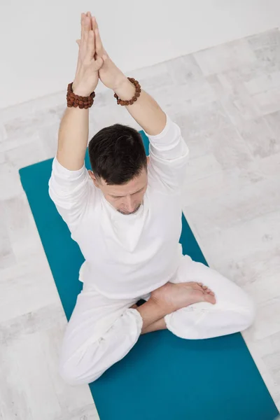 Un hombre vestido de blanco sobre un fondo blanco con las manos dobladas en el pecho. Meditación y oración, yoga . — Foto de Stock