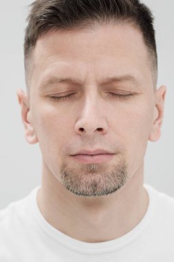 Beyaz giysili bir sakallı brunet adamın yüzü, gözleri kapalı kapat.