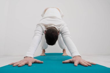 Beyaz giysili bir adam egzersizleri yapar. Yoga asanas ve pozlar germe ve meditasyon için. Parlak spor sınıf fonunda.