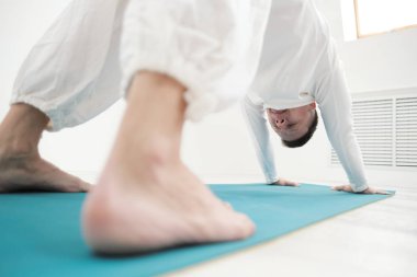 Beyaz giysili bir adam egzersizleri yapar. Yoga asanas ve pozlar germe ve meditasyon için.