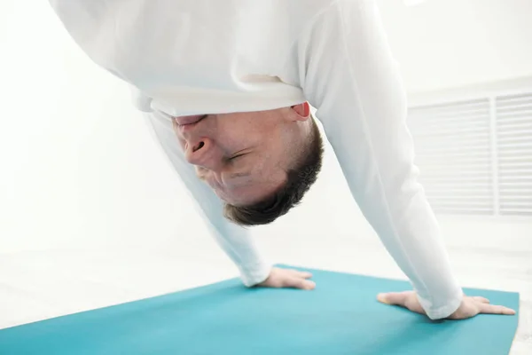 Un hombre con ropa blanca hace ejercicios. Asanas y poses de yoga para estirar y meditar . — Foto de Stock