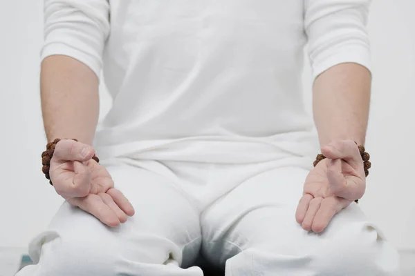 Концепція йоги та медитації. Крупним планом, руки чоловіка в білому одязі, складені в молитві. Білий фон і жовтий-міні гумовий килимок . — стокове фото