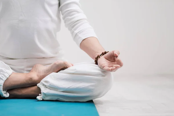 Yoga ve meditasyon kavramı. Yakın çekim, Beyaz giysili bir adam elinde dua katlanmış. Beyaz arka plan ve sarı-mini paspas. — Stok fotoğraf
