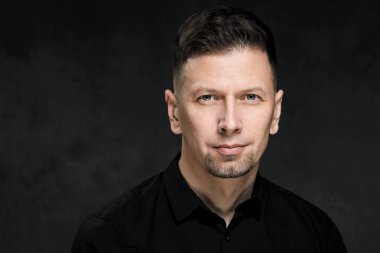 Bir karanlık sanatsal arka plan yakın çekim 40 yaşında yakışıklı bir adam portresi. Esmer, gri saçlı, Siyah sakallı ve siyah gömlek.