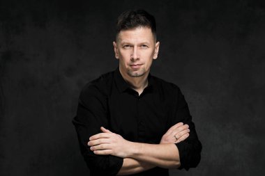 Bir karanlık sanatsal arka plan yakın çekim 40 yaşında yakışıklı bir adam portresi. Esmer, gri saçlı, Siyah sakallı ve siyah gömlek. Kendinden emin ve ciddi bir görünüm.