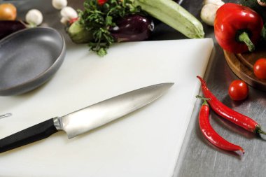 Sebze ve şefler bıçakla Restoran altındaki beyaz kesme tahtası üzerinde yalan.