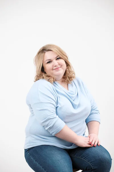 Jeune femme obèse en vêtements bleus décontractés sur fond blanc dans le studio. Bodypositif . — Photo