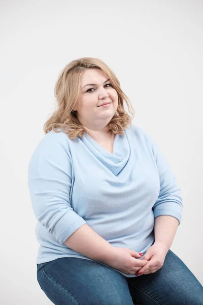 Jeune femme obèse en vêtements bleus décontractés sur fond blanc dans le studio. Bodypositif . — Photo