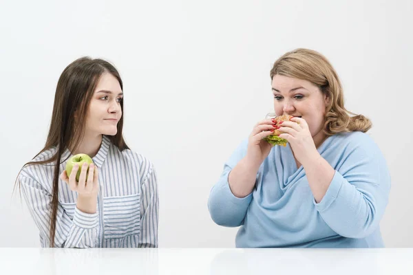 Slender girl eats healthy food, Fat woman eats harmful fast food. On a white background, the theme of diet and proper nutrition.
