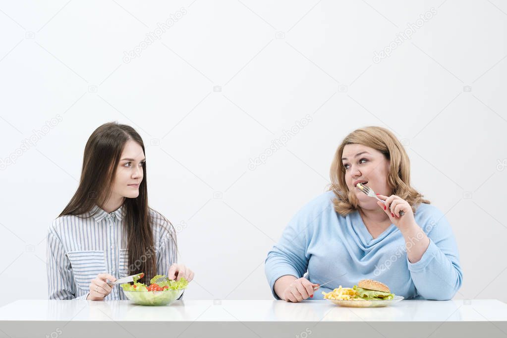 Slender girl eats healthy food, Fat woman eats harmful fast food. On a white background, the theme of diet and proper nutrition.