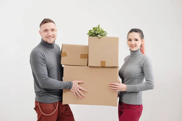 Una mujer joven y un hombre llevan cajas de cartón pesadas con cosas. Apartamento de luz blanca. Se ríen y besan . —  Fotos de Stock