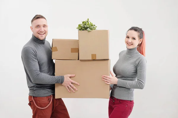 Una mujer joven y un hombre llevan cajas de cartón pesadas con cosas. Apartamento de luz blanca. Se ríen y besan . —  Fotos de Stock