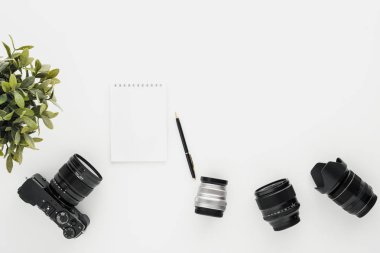 Beyaz bir masada MoCap iş fotoğrafçı. Düz aynasız kamera, birkaç lensler ve bir kalem ile bir Notebook yatıyordu.