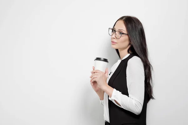 Hermosa chica morena atractiva joven con pelo largo y rizado con gafas en el fondo de una pared blanca . — Foto de Stock